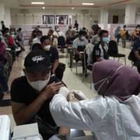 A health care worker administers a dose of the AstraZeneca COVID-19 vaccine in Jakarta in May.  | BLOOMBERG 