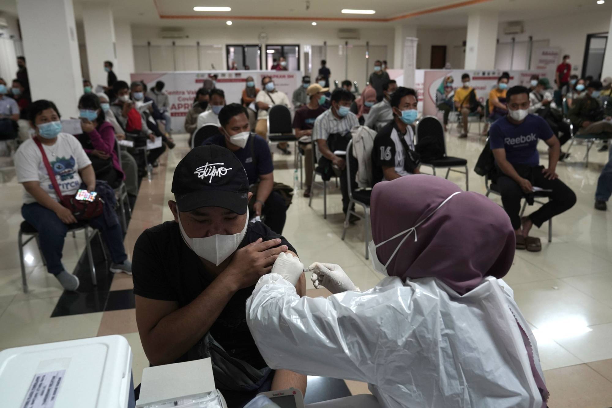 A health care worker administers a dose of the AstraZeneca COVID-19 vaccine in Jakarta in May. | Bloomberg 