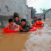Soldiers evacuate children stranded by floodwaters in Weihui in Xinxiang, Henan province, China, on Thursday.  | CNSPHOTO / VIA REUTERS  