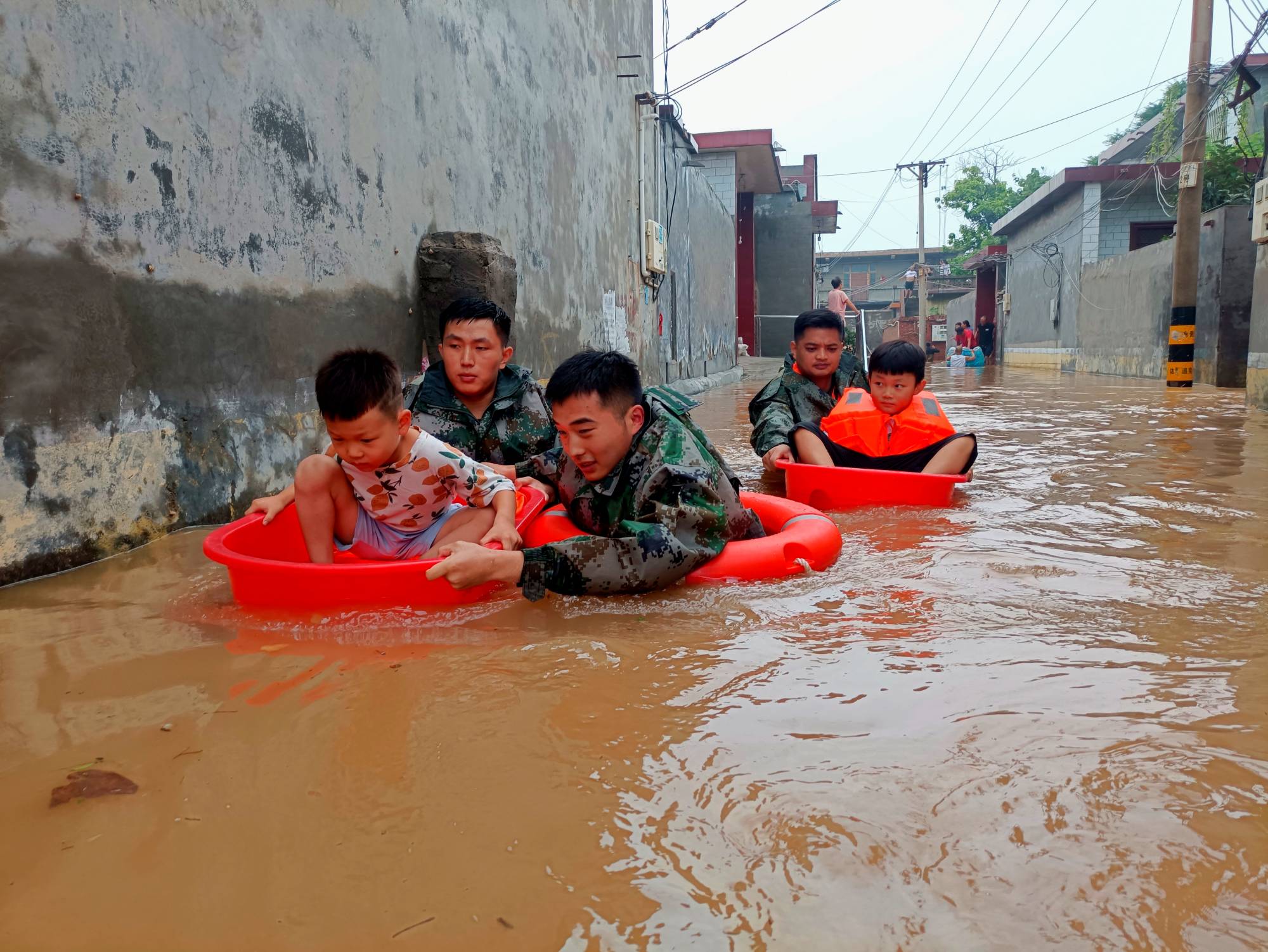 Soldiers evacuate children stranded by floodwaters in Weihui in Xinxiang, Henan province, China, on Thursday. | cnsphoto / via REUTERS 