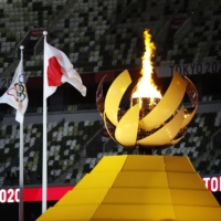 The Olympic and Japan flags fly in from the the flame of hope at the Tokyo Games\' opening ceremony. | KYODO