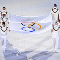Olympians including Japanese badminton star Kento Momoto (left, front) carry the Olympic flag toward the main stage. | KYODO