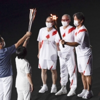 Baseball legends — (from right) Hideki Matsui, Shigeo Nagashima and Sadaharu Oh  —  transfer the Olympic flame to medical workers during the finale of the opening ceremony. | KYODO