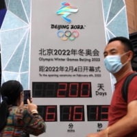 A woman uses her phone in front of a countdown clock for the 2022 Beijing Winter Olympics in the Chinese capital on Monday. | REUTERS