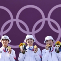 South Korean gold medalists An San, Jang Minhee and Kang Chae Young of South Korea celebrate on the podium. | REUTERS