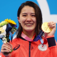 Swimming gold medalist Yui Ohashi of Japan poses on the podium after winning the women\'s 400 meter individual medley on Sunday. The IOC said Sunday it has relaxed COVID-19 protocols at the Tokyo Olympics to allow medalists to take off their masks for up to 30 seconds on the podium to be photographed. | REUTERS