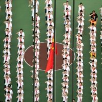 Children line up for a flag-raising ceremony in Shanghai. China has announced broad reforms of private-sector education.  | GETTY IMAGES / VIA BLOOMBERG 
