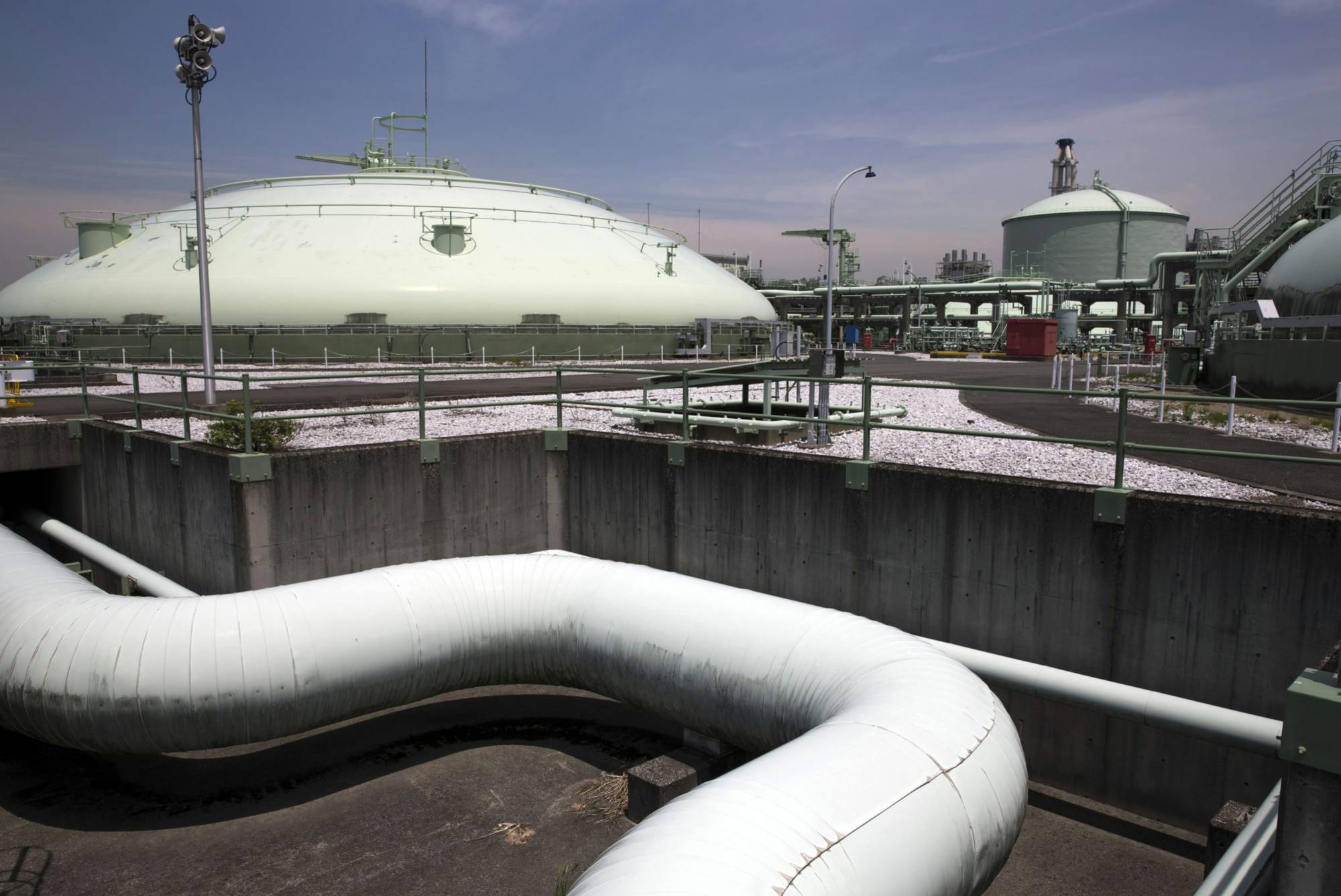 An in-ground liquefied natural gas tank (left), and an above ground storage type LNG tank stand at Tokyo Gas Co.'s Negishi LNG terminal in Yokohama. | BLOOMBERG