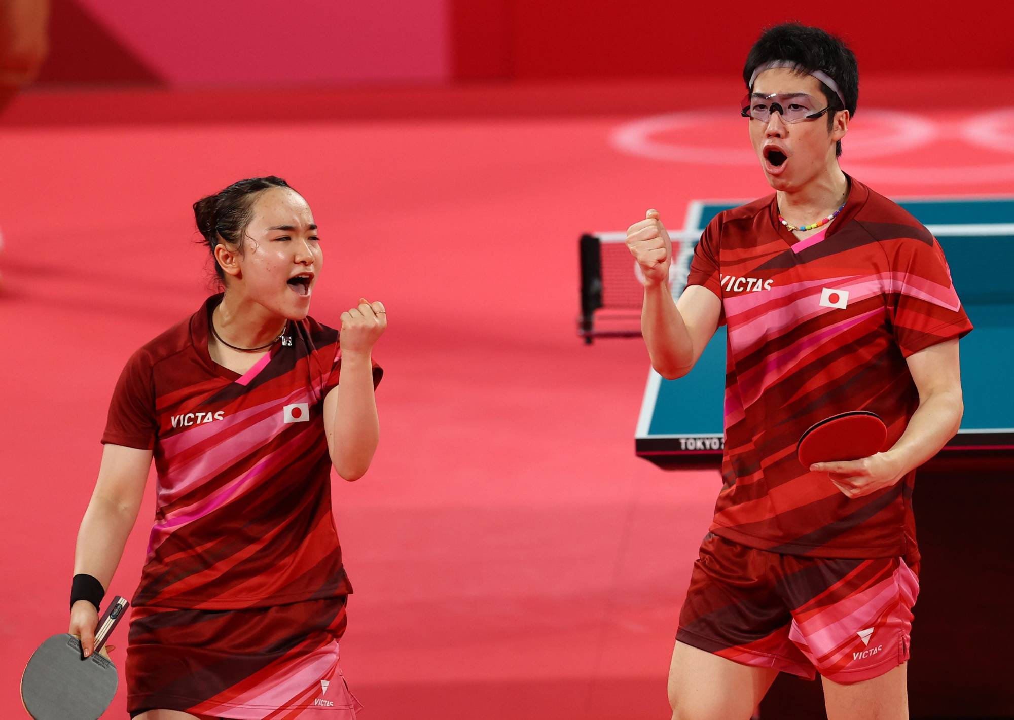 Japan's Mima Ito and Jun Mizutani pump their fists during the mixed doubles Olympic gold-medal match on Monday in Tokyo. | REUTERS