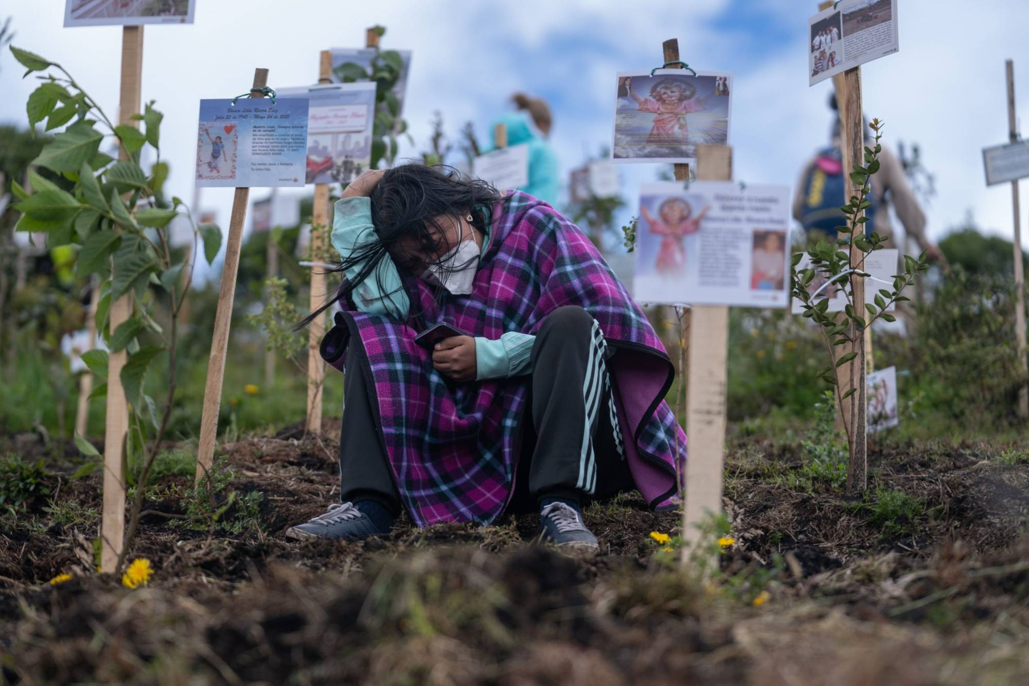 A mourner grieves over the scattered ashes of a COVID-19 victim at a nature preserve in Colombia, which has reported over 118,000 virus-related deaths. | BLOOMBERG 