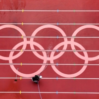 A man washes the track at the Olympic Stadium in Tokyo on Monday, ahead of athletics events in the Tokyo 2020 Olympic Games. | AFP-JIJI 