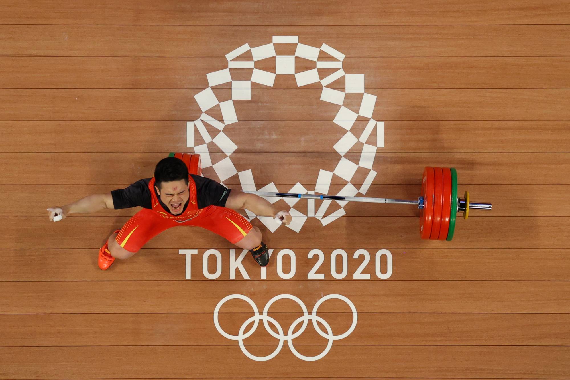 China's Shi Zhiyong celebrates during the men's 73-kg weightlifting | POOL VIA REUTERS