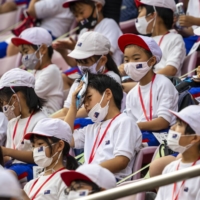 Young Japanese students try to cool off while watching the New Zealand vs. Republic of Korea men’s soccer match at Ibaraki Kashima Stadium in Kashimia. | DOUG MILLS/THE NEW YORK TIMES