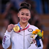 Sunisa Lee celebrates on the podium after winning the women\'s all-around title at the Tokyo Olympics at Ariake Gymnastics Centre on Wednesday. | REUTERS