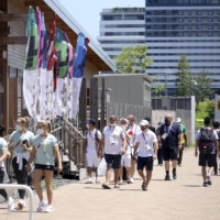 Athletes and staff walk in the athletes village in Tokyo on July 21. | GETTY IMAGES / VIA KYODO