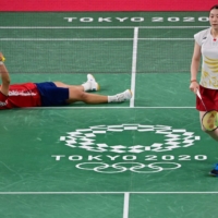 China\'s Huang Dongping celebrates after winning her mixed doubles badminton semifinal with Wang Yilyu against Japan\'s Arisa Higashino (right) and Yuta Watanabe at the Musashino Forest Sports Plaza in Tokyo on Thursday. | AFP-JIJI