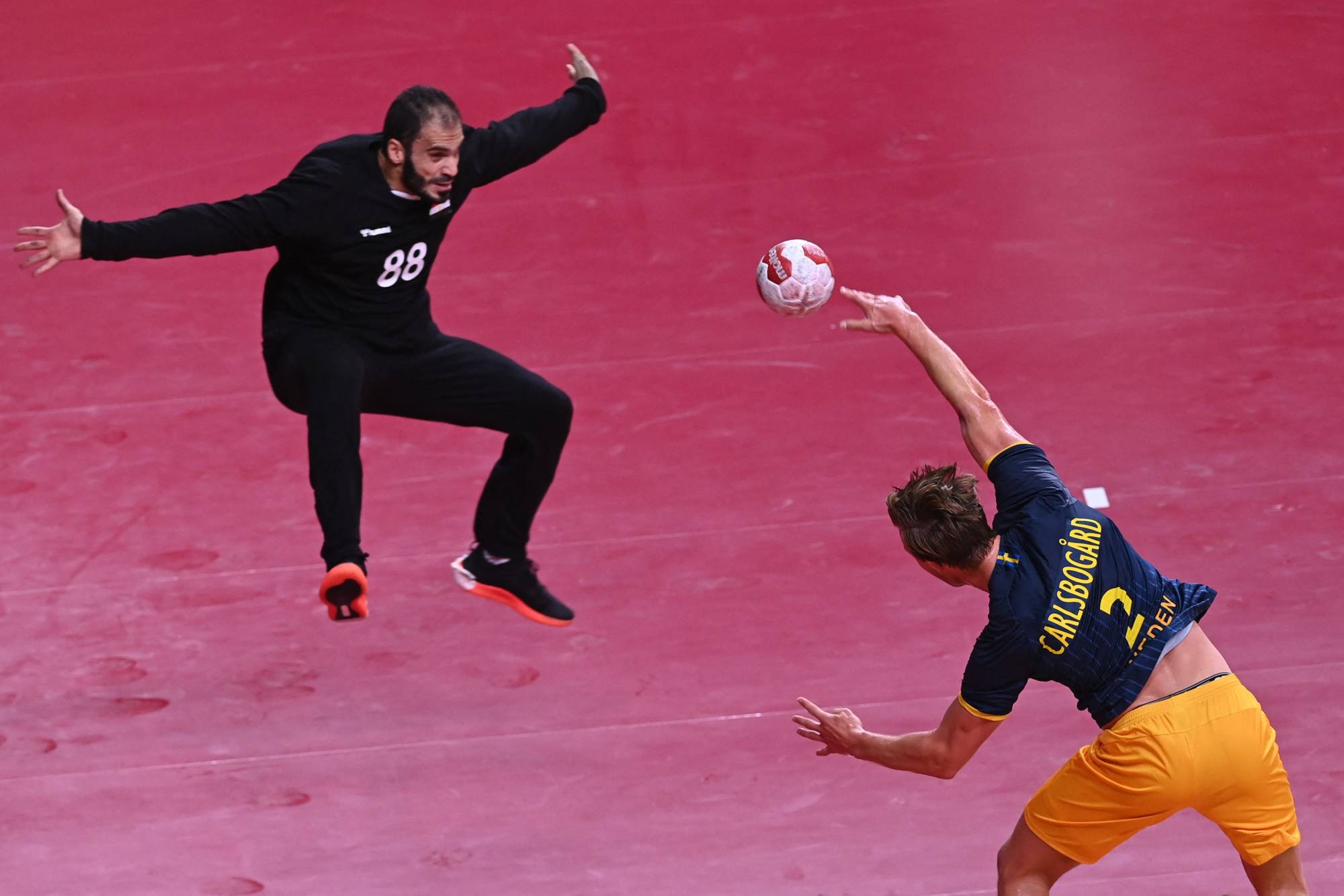 Egypt's goalkeeper Karim Hendawy (left) tries to block a shot by Sweden's Jonathan Carlsbogard during a men's preliminary handball match | AFP-JIJI