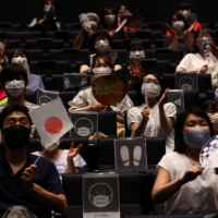 People watch a live broadcast of a volleyball match between Japan and Poland on a large screen during a public viewing event for the Tokyo Olympics at a theater in Takasaki, Gunma Prefecture, on Friday. | REUTERS