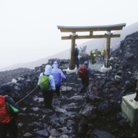 Climbers who made it to the summit of Mount Fuji head back down amid bad weather early Thursday. | KYODO