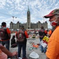 Demonstrators wearing orange in solidarity with survivors of residential schools gather at a memorial in front of Parliament Hill on Canada Day, in Ottawa on Thursday.  | BLOOMBERG