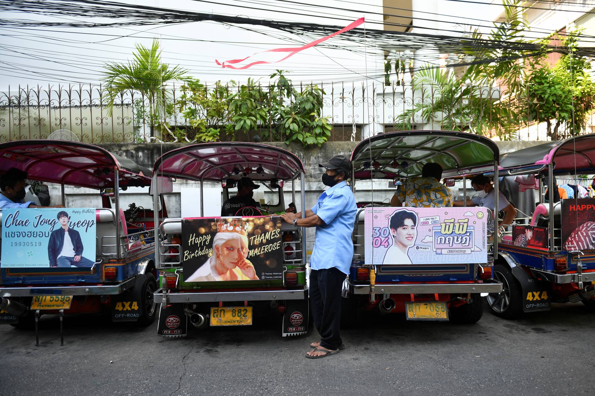 Tuk-tuk drivers, with their vehicles decorated with banners of Thai and Korean stars, wait for customers in Bangkok in May.  | REUTERS 