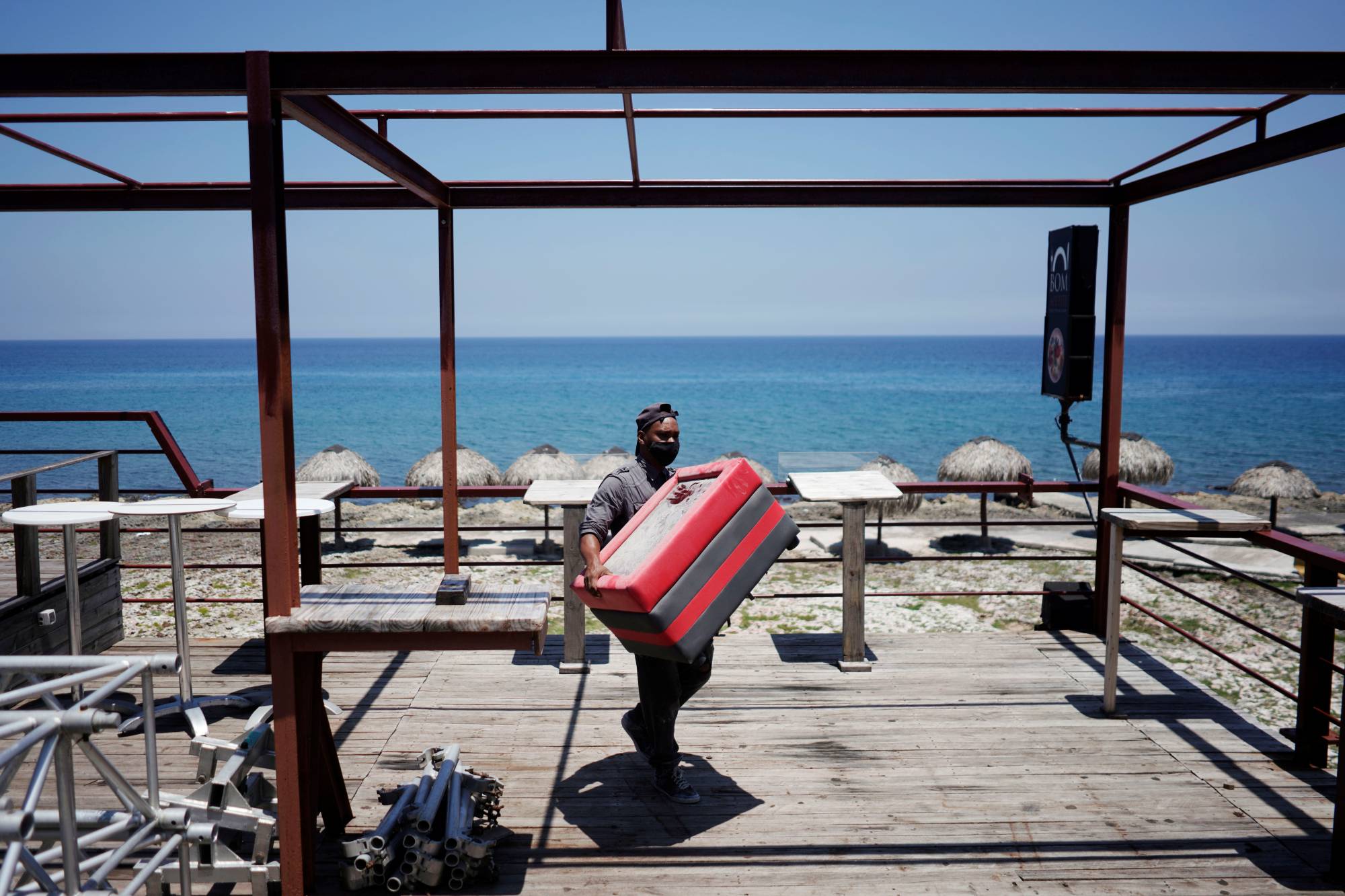 A worker removes furniture from a restaurant terrace as Storm Elsa approaches the island, in Havana on Saturday.  | REUTERS 