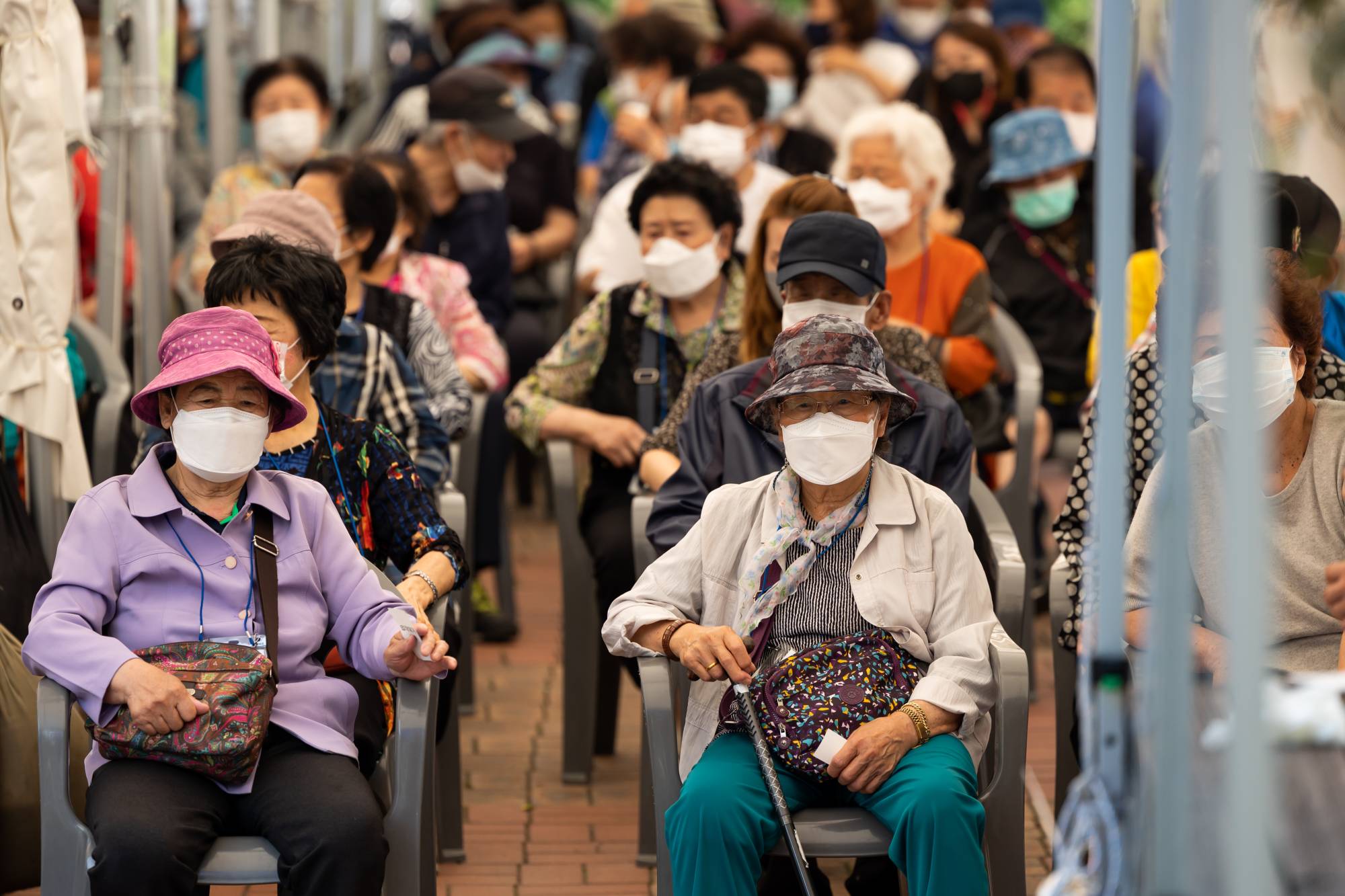 Older residents wait to receive a dose of the Pfizer-BioNTech COVID-19 vaccine outside an inoculation site at the Guro Arts Valley Theater in the Guro district of Seoul on Tuesday. | BLOOMBERG