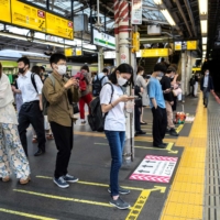Passengers wait for a train at JR Shinjuku Station in Tokyo on June 17. | AFP-JIJI