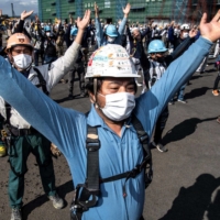Workers take part in daily physical exercises performed before starting their shift at a construction site in Kanagawa Prefecture. | AFP-JIJI