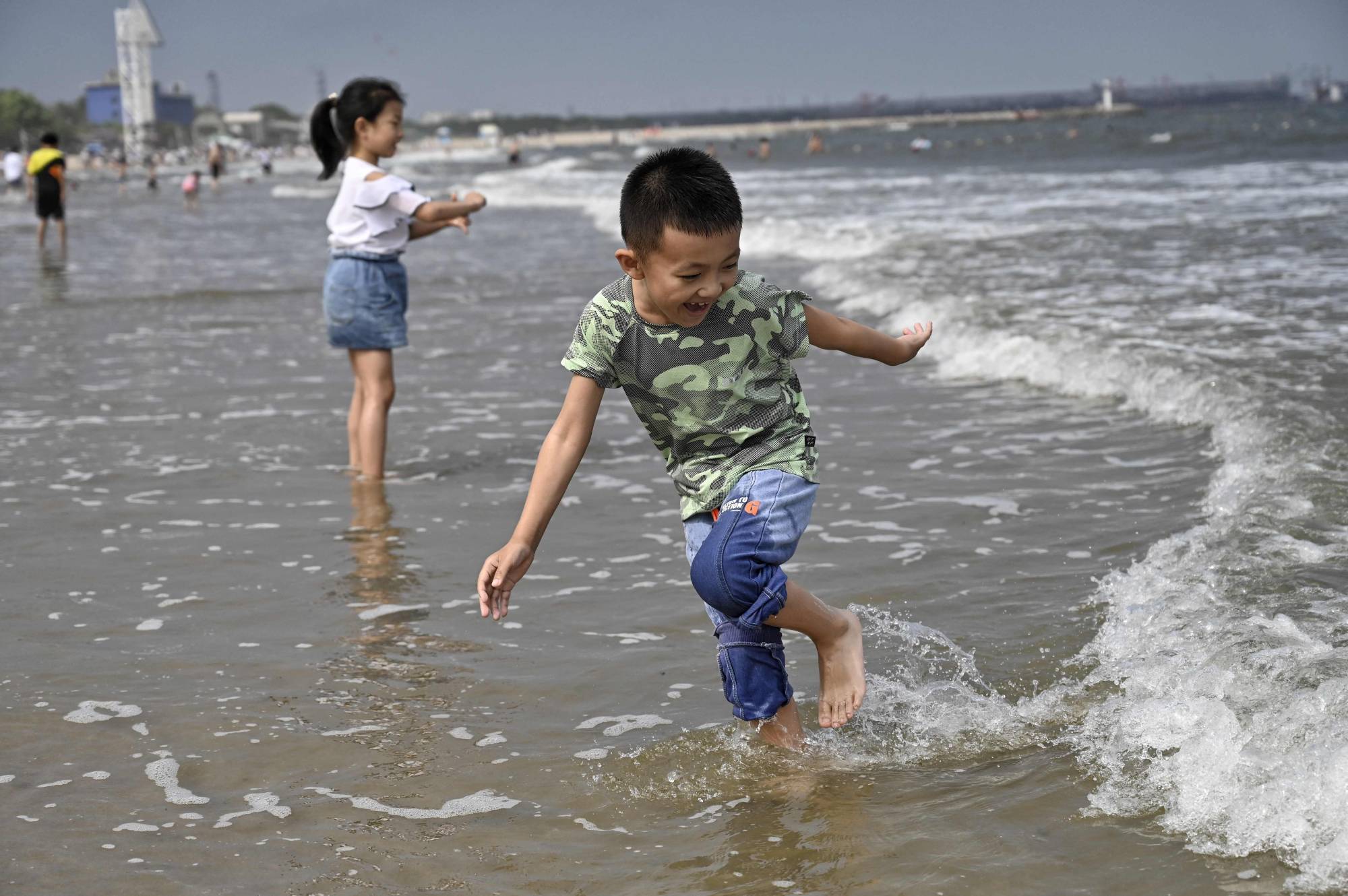 Children play on a beach in Qinhuangdao, in northern China's Hebei province, on Sunday. | AFP-Jiji
