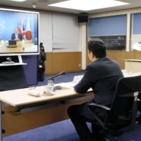 Foreign Minister Toshimitsu Motegi (front right) and Defense Minister Nobuo Kishi hold a videoconference with their British counterparts Dominic Raab (right on the screen) and Ben Wallace on Feb. 3. | POOL / VIA KYODO