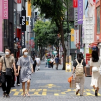 People wearing masks walk in a shopping district in Seoul on Friday. | REUTERS