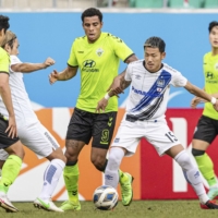 Gamba midfielder Yosuke Ideguchi contends for the ball against several Jeonbuk players in Tashkent on Saturday. | KYODO