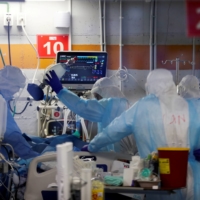 Medical workers, seen through a window of an observation room, treat COVID-19 patients at the Critical Care Coronavirus Unit at Sheba Medical Center in Ramat Gan, Israel, in February. | REUTERS 