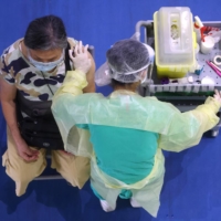 A medical worker administers a dose of the AstraZeneca COVID-19 vaccine to a woman during a vaccination session for people over 75 years old, at a stadium in New Taipei City, Taiwan, on June 25. | REUTERS