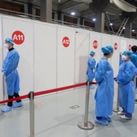 Medical workers wait at booths during a government-organized session for foreign nationals to receive a COVID-19 vaccine, at a vaccination site in Beijing on March 23. | REUTERS