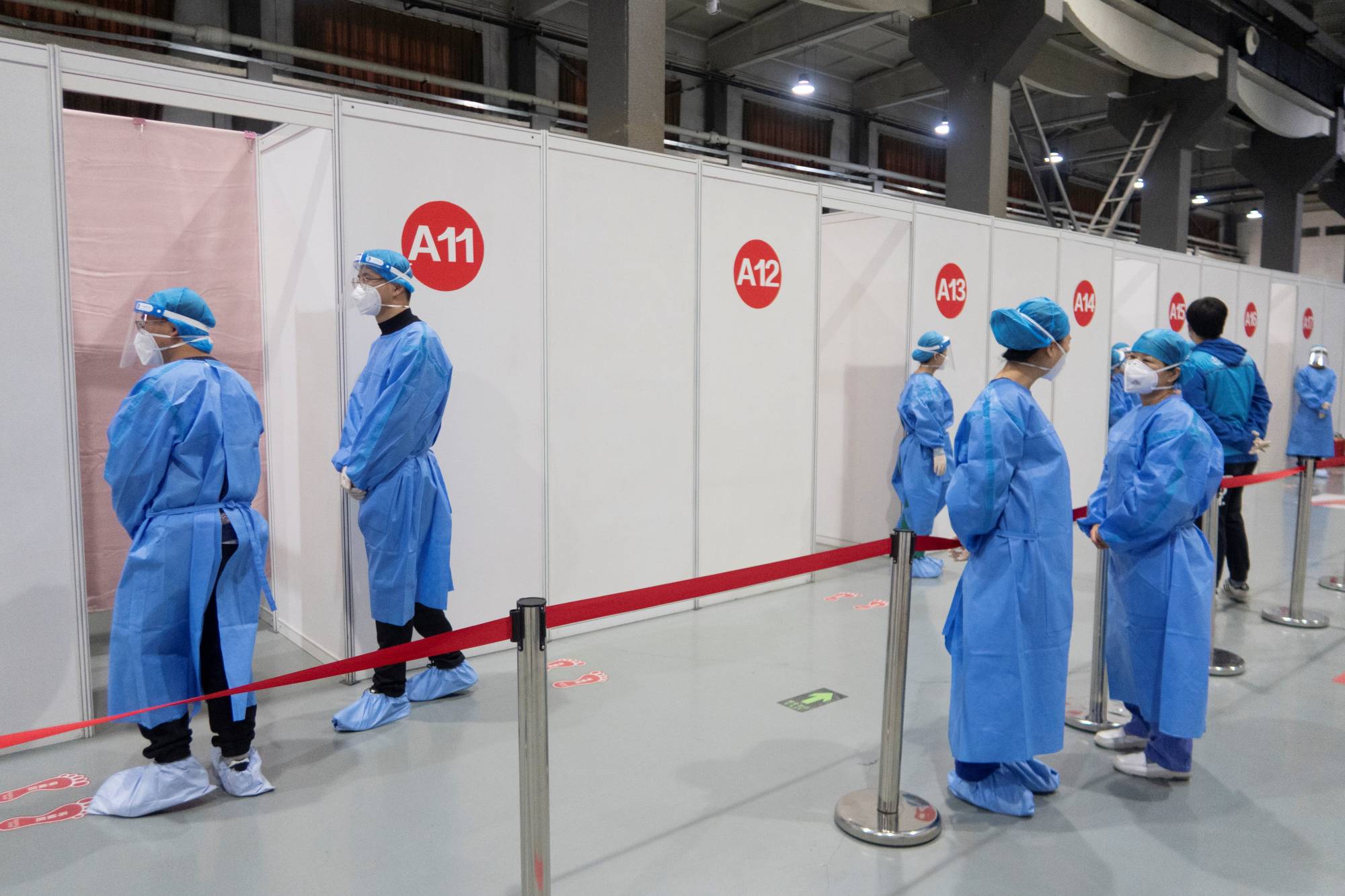 Medical workers wait at booths during a government-organized session for foreign nationals to receive a COVID-19 vaccine, at a vaccination site in Beijing on March 23. | REUTERS