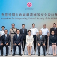 Carrie Lam (center), flanked by Security Secretary Chris Tang (standing third from right), Immigration Director Au Ka-wang (standing second right) and Customs Commissioner Hermes Tang (standing second left) pose for a photo in July 2020. | BLOOMBERG