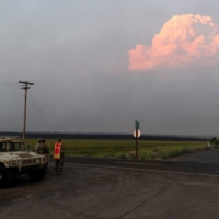 Members of the U.S. National Guard monitor a road blockade in Bly, Oregon, on Thursday as smoke from the Bootleg fire looms in the distance. | REUTERS