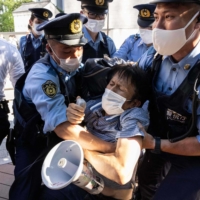 Police officers block an activist as protesters walk toward the hotel where IOC President Thomas Bach is staying, in Tokyo on Saturday.  | AFP-JIJI