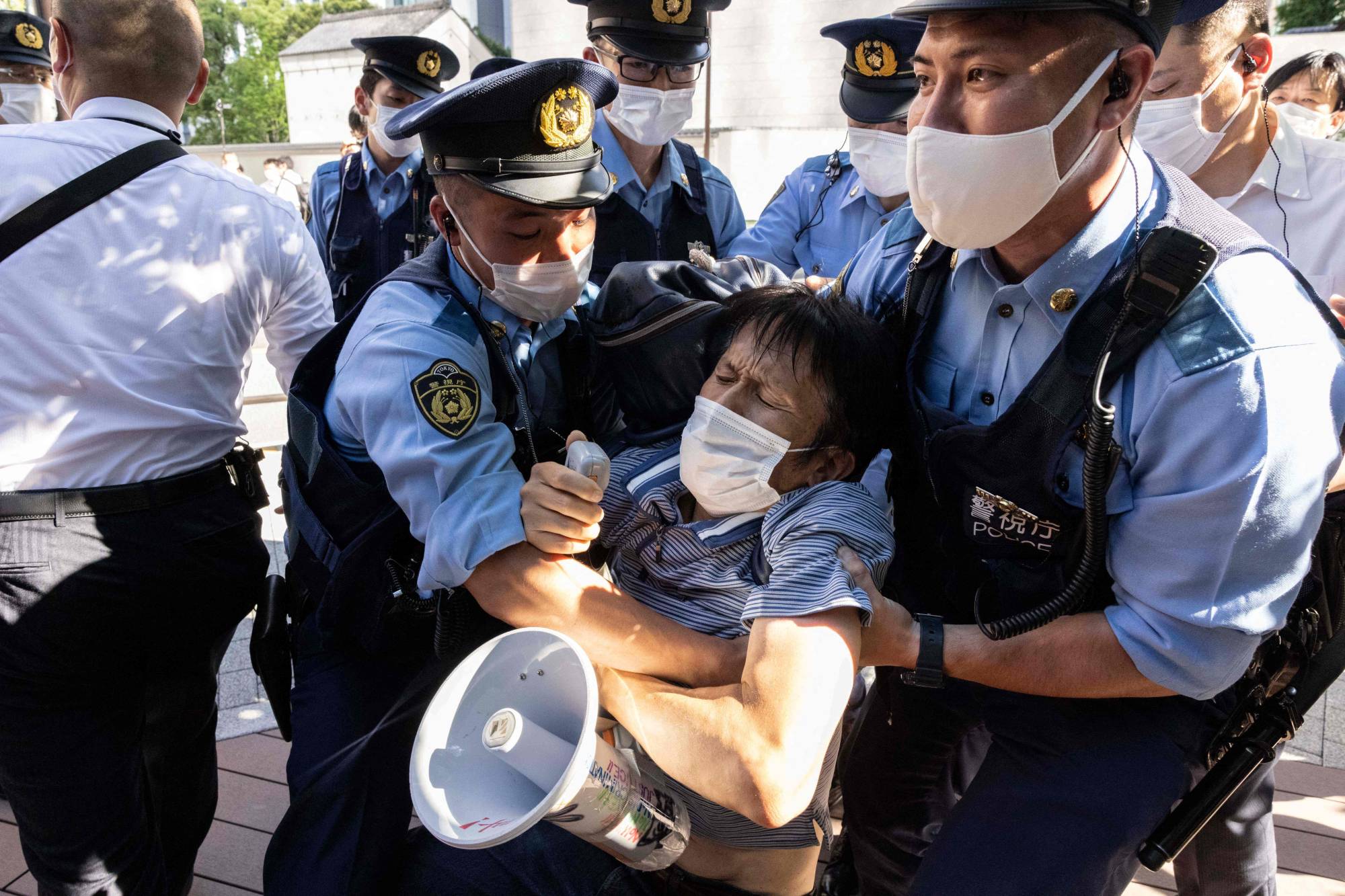 Police officers block an activist as protesters walk toward the hotel where IOC President Thomas Bach is staying, in Tokyo on Saturday. | AFP-JIJI