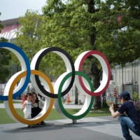 People pose in front of the Olympic rings located near the National Stadium in Tokyo\'s Shinjuku Ward. | RYUSEI TAKAHASHI
