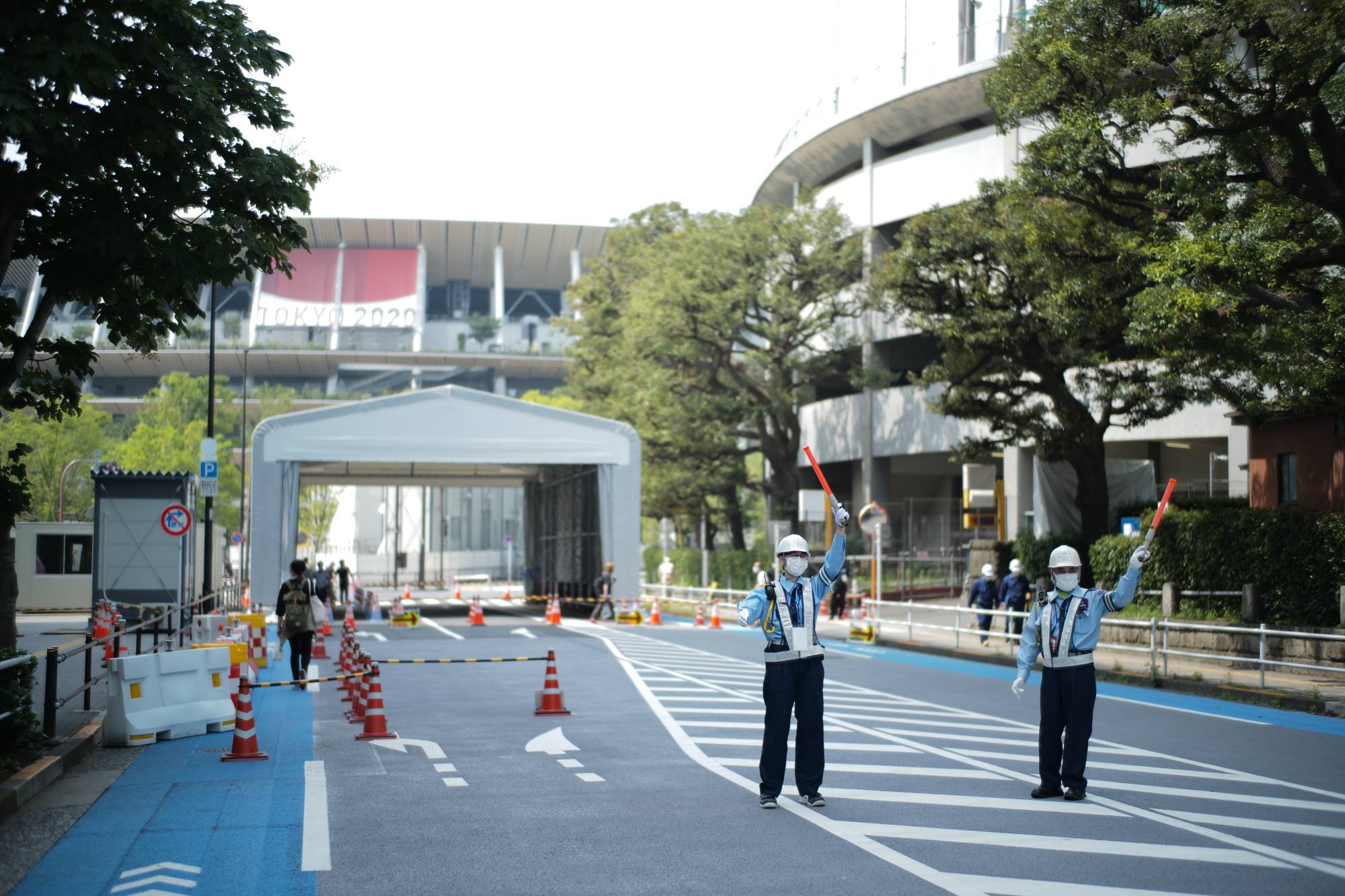 Guards marshal traffic on a blocked road in front of the National Stadium in early July, where restrictions have been put in place leading up to the opening ceremony of the Tokyo Games. | Ryusei Takahashi 