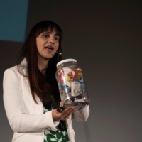 Priyanka Bakaya, founder of Renewlogy, holds a jar of mixed recyclables as she speaks at the 2015 TEDx Amherst event at the University of Massachusetts in April 2015. | CADE BELISLE / THE MASSACHUSETTS DAILY COLLEGIAN / VIA REUTERS