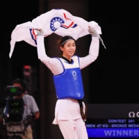 Lo Chia-Ling of Taiwan celebrates with the Chinese Taipei flag after winning bronze in the women\'s featherweight division of taekwondo.  | REUTERS