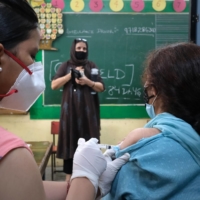 A health worker administers a dose of a COVID-19 vaccine at Navyug School in New Delhi on July 22. | BLOOMBERG 