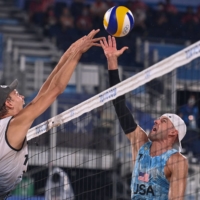Germany\'s Julius Thole (left) attempts to block a shot from U.S.\'s Jacob Gibb during their men\'s beach volleyball round | AFP-JIJI