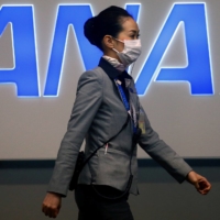 An employee passes in front of All Nippon Airways logo at Kansai International Airport in Osaka in March 2020. | REUTERS