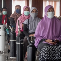 People wait to get their oxygen cylinders refilled in Karanganyar, Central Java province, Indonesia, on July 30. | MOHAMMAD AYUDHA / VIA ANTARA FOTO / VIA REUTERS. 