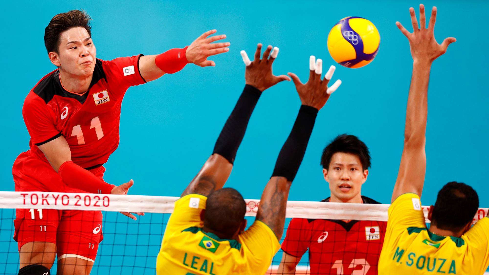 Yuji Nishida of Japan hits the ball as Brazil's Leal and Mauricio Souza go up for a block during their men's quarterfinal match on Tuesday. | REUTERS